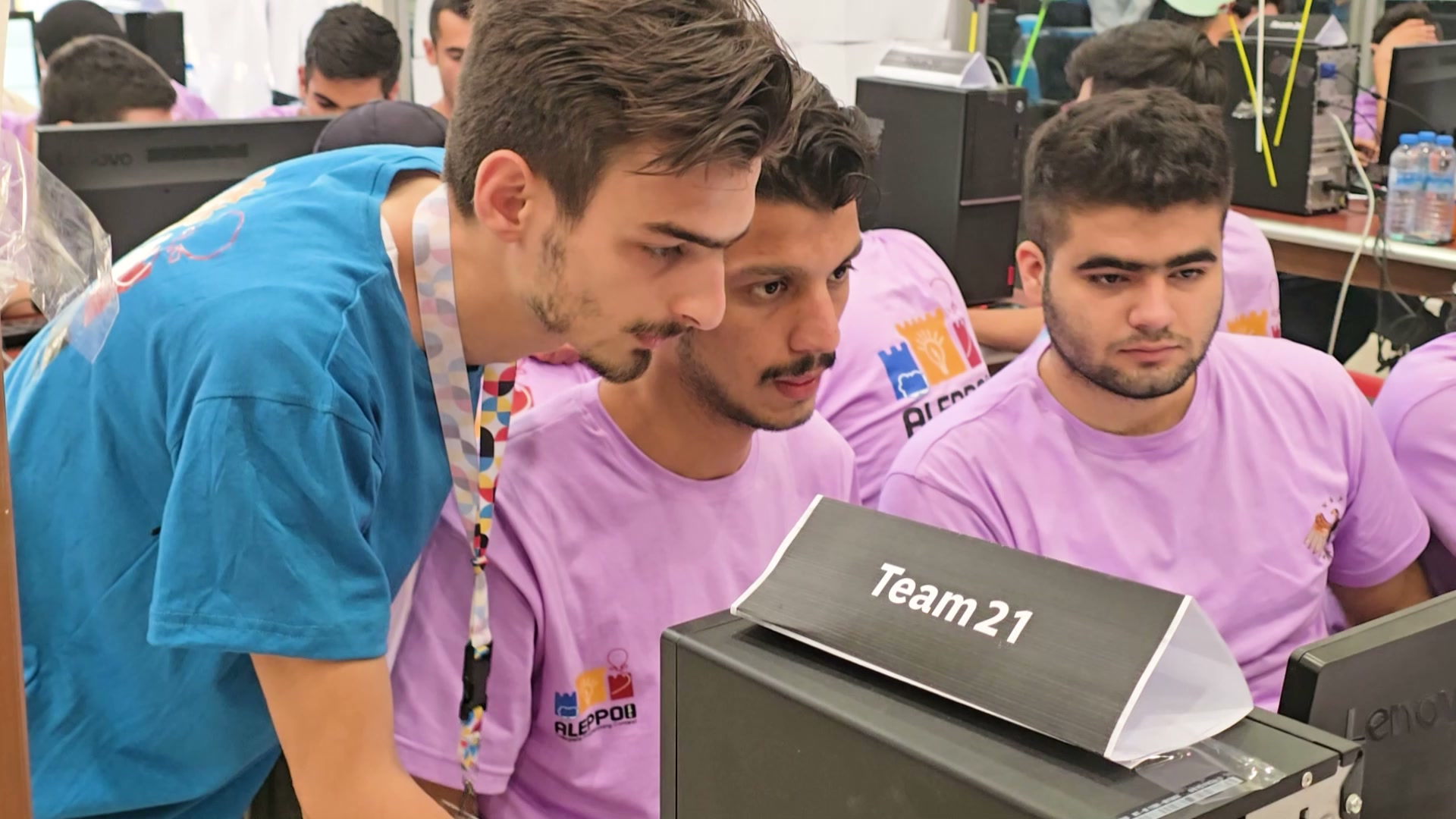 A coach working through a problem with a team at its workstation